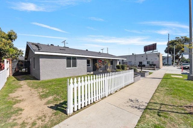 view of front facade featuring stucco siding, a fenced front yard, a front lawn, and a gate