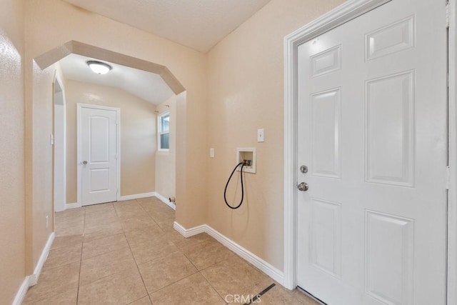 entryway featuring light tile patterned floors, baseboards, and arched walkways