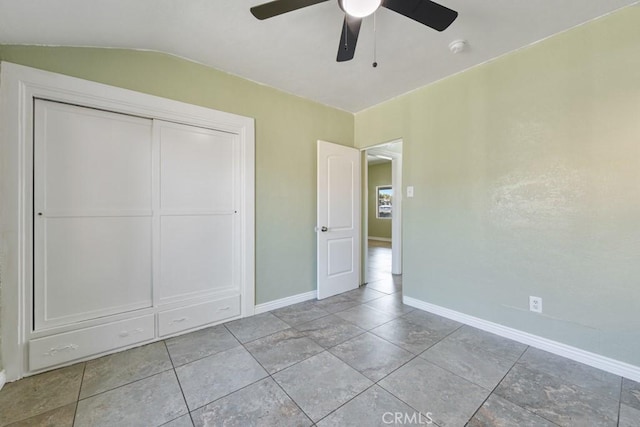 unfurnished bedroom with tile patterned floors, a ceiling fan, a closet, baseboards, and lofted ceiling