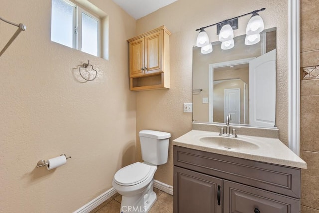 bathroom featuring toilet, tile patterned flooring, baseboards, vanity, and a textured wall