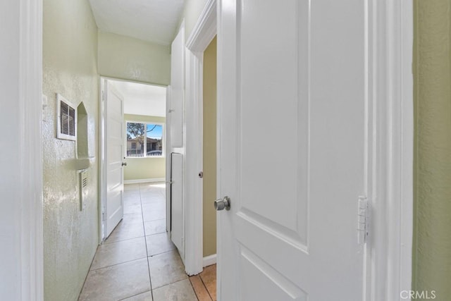 hall featuring light tile patterned flooring, visible vents, and baseboards