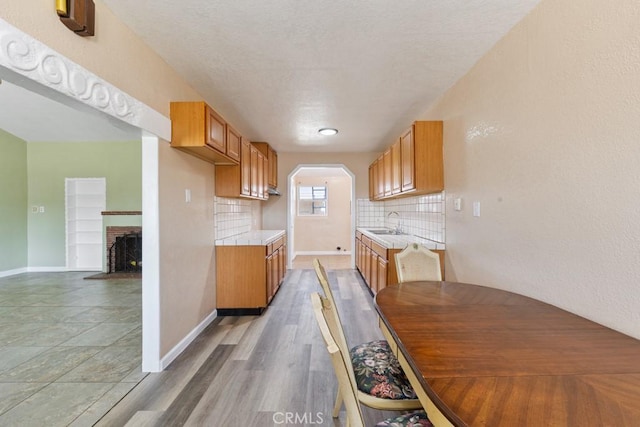 kitchen with brown cabinetry, backsplash, light countertops, and a sink