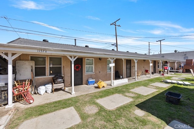 back of house featuring stucco siding, a yard, and a patio area