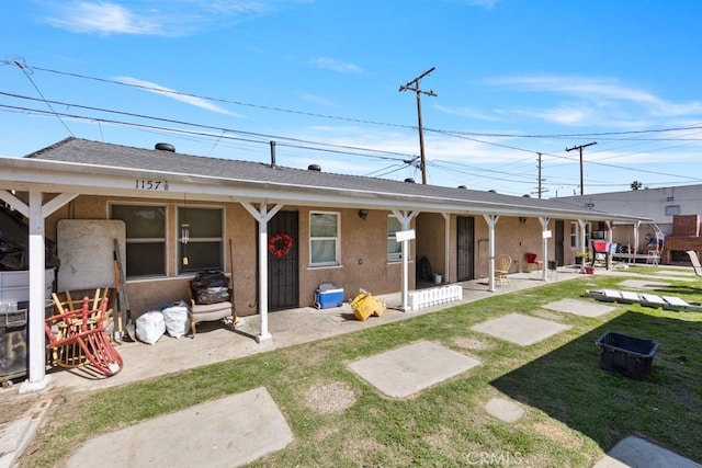 back of property featuring a patio area, a lawn, and stucco siding