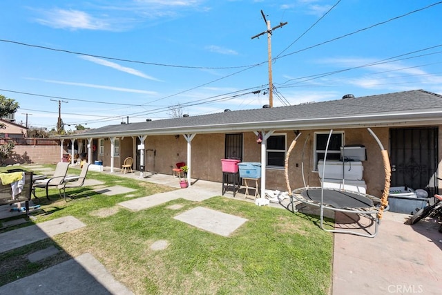 back of property featuring a patio area, stucco siding, a lawn, and a shingled roof