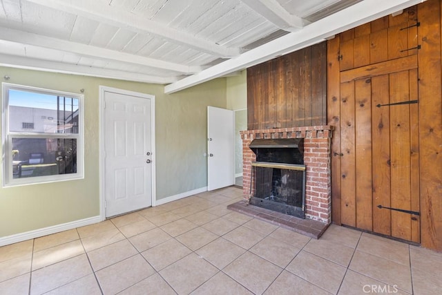 unfurnished living room featuring beam ceiling, a brick fireplace, baseboards, and light tile patterned flooring