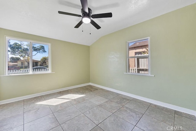 tiled empty room with plenty of natural light, baseboards, and vaulted ceiling