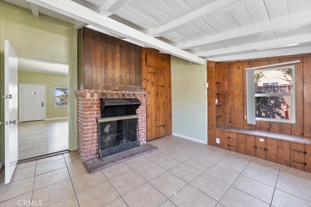 unfurnished living room featuring a wealth of natural light, beamed ceiling, wooden walls, and a fireplace