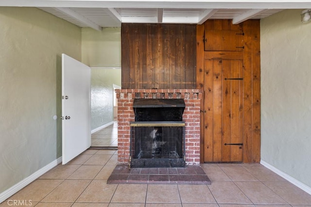 unfurnished living room featuring light tile patterned floors, beamed ceiling, baseboards, and a fireplace