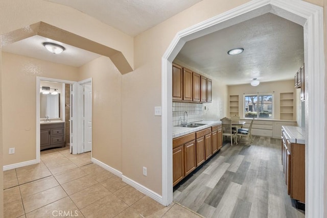 kitchen with a sink, brown cabinets, a textured ceiling, and tile counters