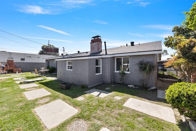 rear view of house with stucco siding, a patio, a lawn, and fence