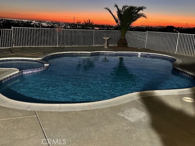 pool at dusk with an in ground hot tub