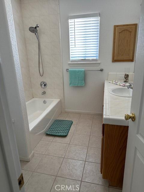 bathroom featuring tile patterned flooring, vanity, and tiled shower / bath