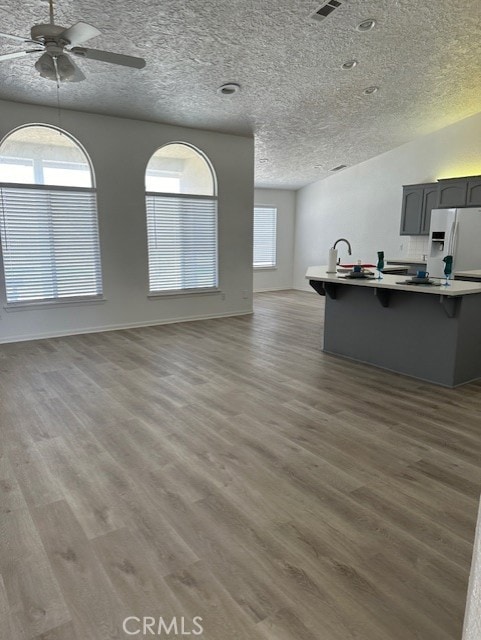 kitchen with a kitchen breakfast bar, a textured ceiling, ceiling fan, light hardwood / wood-style floors, and white fridge with ice dispenser