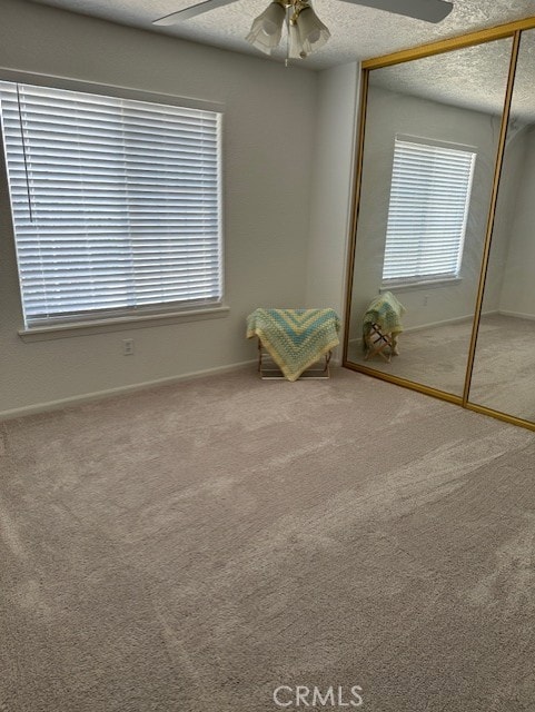 interior space with carpet flooring, a textured ceiling, a closet, and ceiling fan