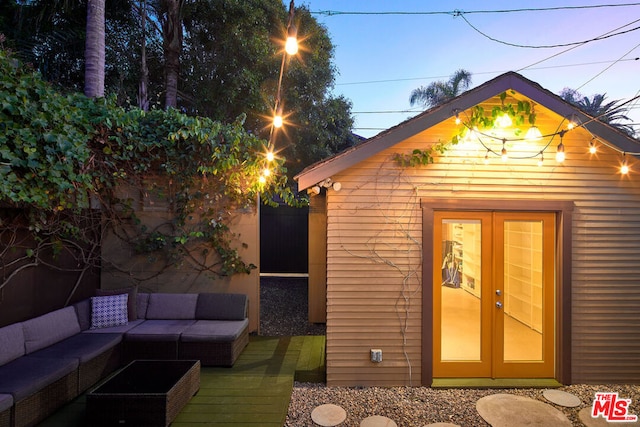 outdoor structure at dusk with outdoor lounge area and french doors