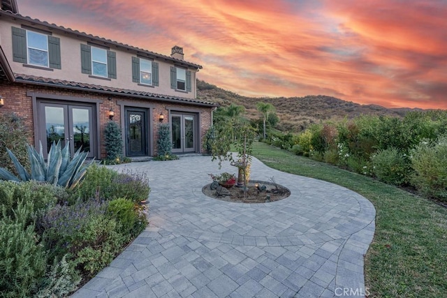 back house at dusk with french doors and a patio area