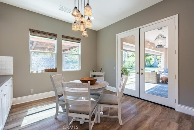 dining space with light hardwood / wood-style flooring, french doors, and an inviting chandelier