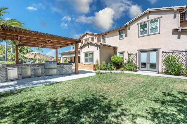 rear view of property featuring a pergola, exterior kitchen, and a lawn