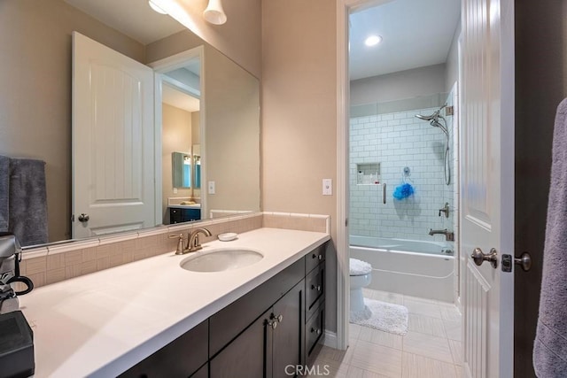 full bathroom featuring tiled shower / bath, tile patterned flooring, vanity, and toilet