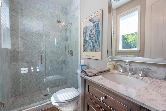 bathroom featuring toilet, a shower with shower door, and vanity