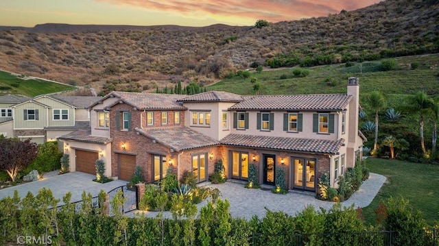 back house at dusk with a mountain view and a garage