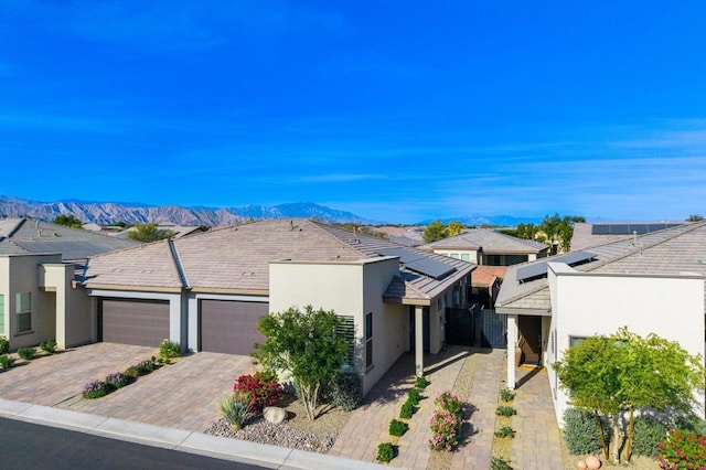 view of front of property featuring a mountain view, a garage, and solar panels