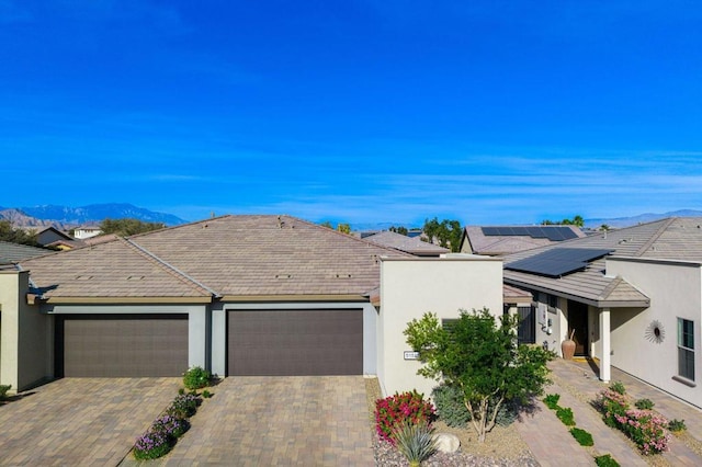 ranch-style house featuring a mountain view, solar panels, and a garage