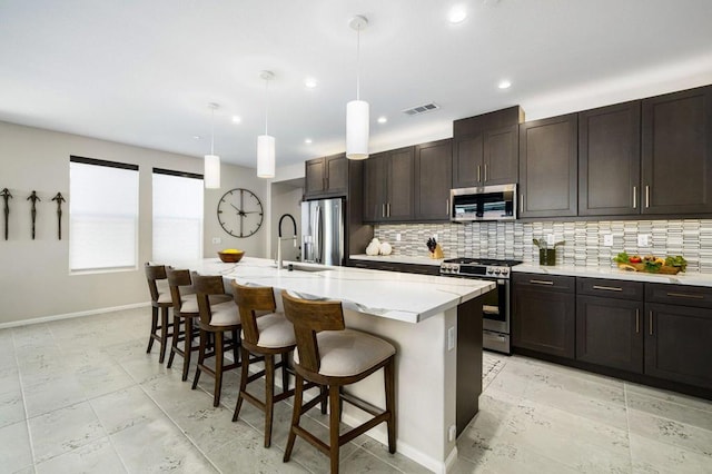 kitchen with pendant lighting, an island with sink, appliances with stainless steel finishes, and a breakfast bar area