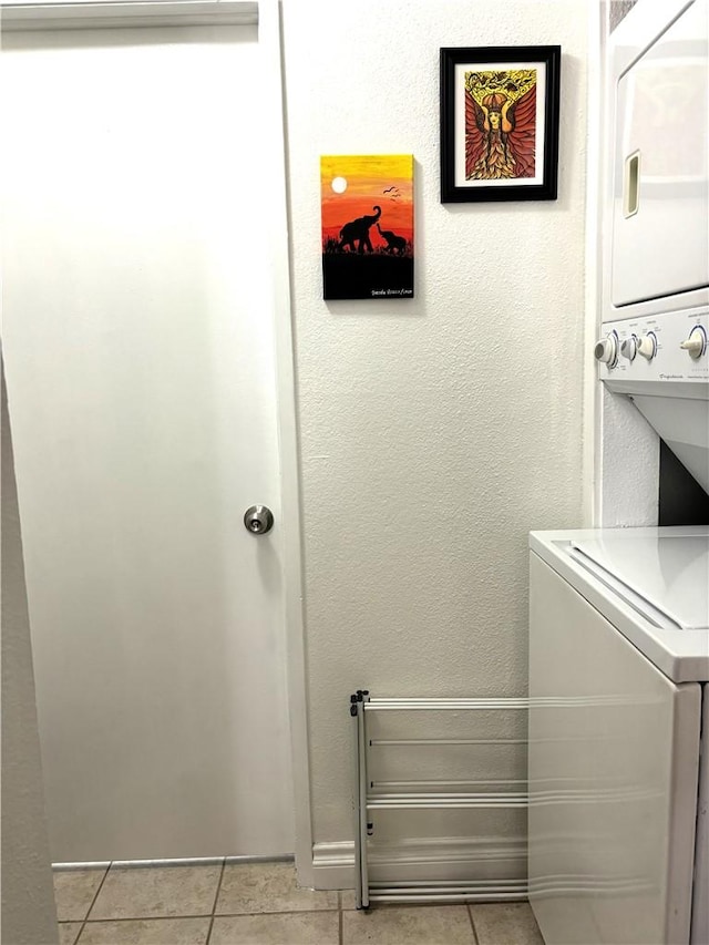 laundry room with stacked washer / dryer, a textured wall, and light tile patterned floors