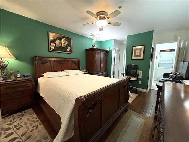 bedroom with stacked washer and dryer, a ceiling fan, baseboards, and dark wood-style floors