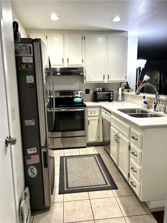 kitchen with under cabinet range hood, appliances with stainless steel finishes, light countertops, and a sink