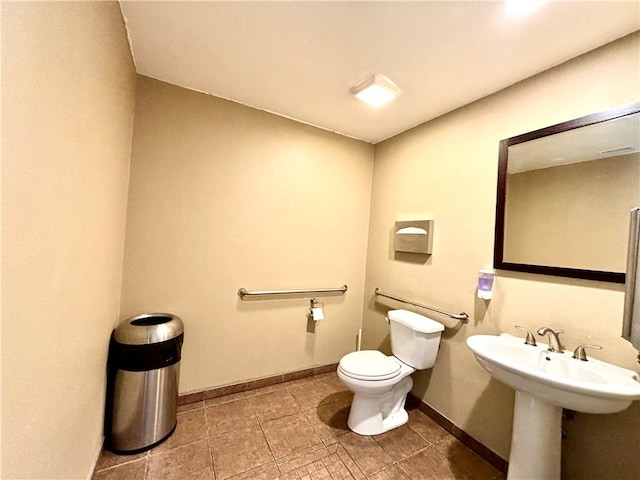 half bath featuring baseboards, a sink, and toilet