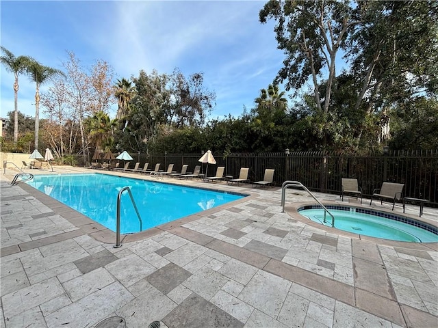 community pool featuring a patio area, fence, and a hot tub