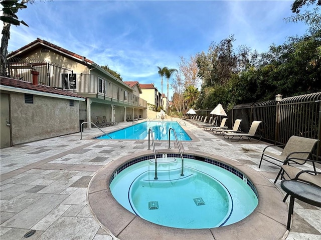 view of pool with a patio area, fence, and a community hot tub