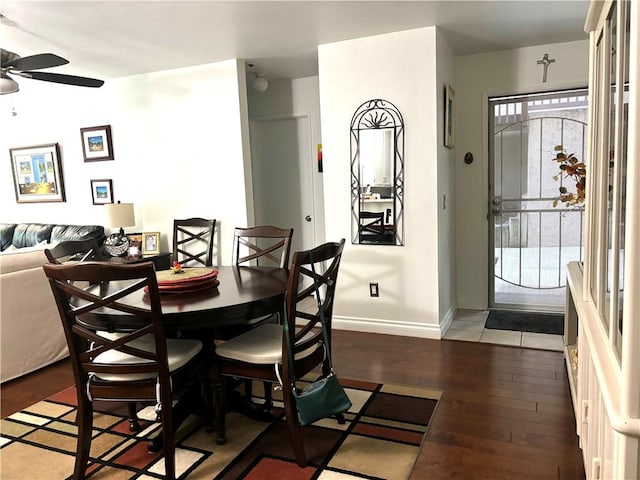 dining area featuring a ceiling fan, baseboards, and dark wood-style flooring