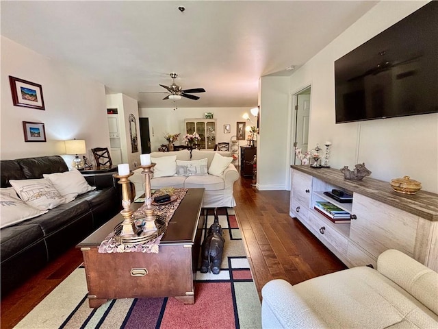 living area with dark wood finished floors, a ceiling fan, and baseboards