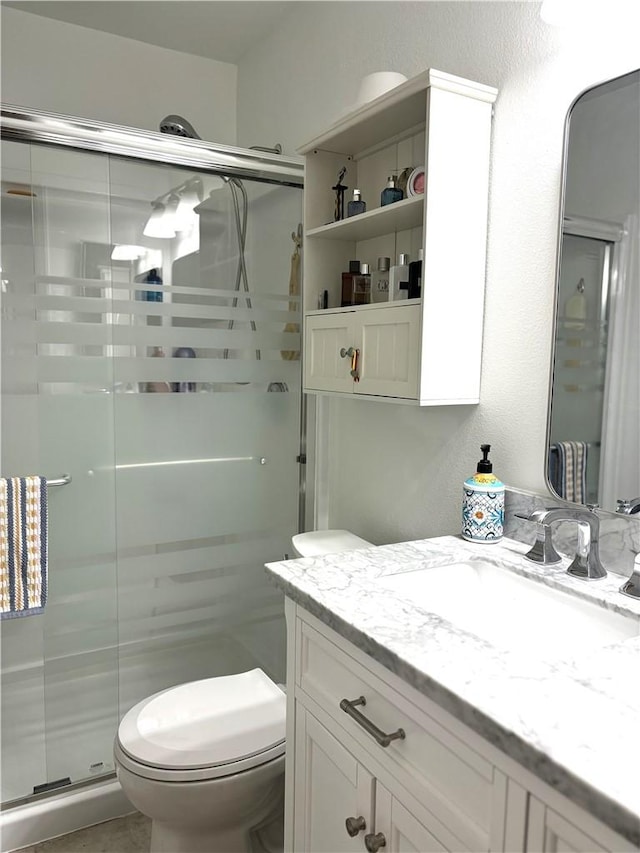 bathroom featuring a stall shower, vanity, and toilet