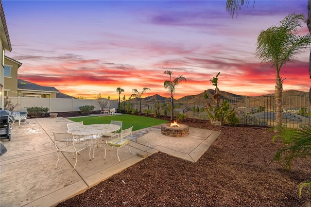 yard at dusk featuring a fire pit, a mountain view, and a patio area