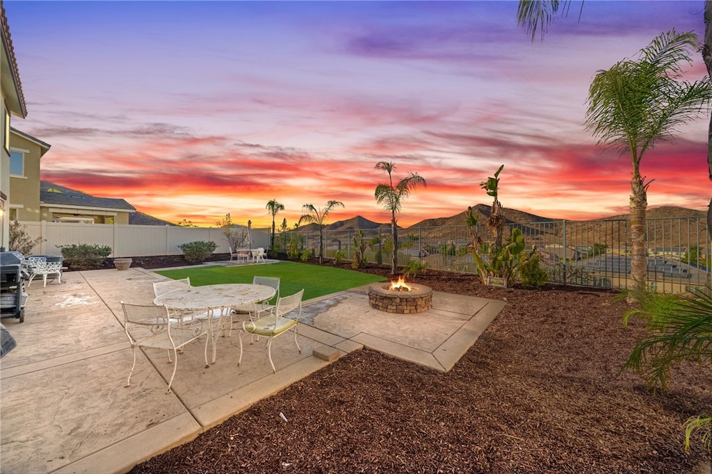 yard at dusk with a mountain view, a patio, and an outdoor fire pit