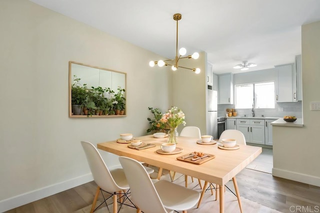 dining room featuring ceiling fan with notable chandelier, light hardwood / wood-style flooring, and sink