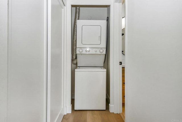 washroom featuring light hardwood / wood-style floors and stacked washing maching and dryer