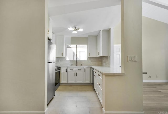 kitchen featuring white cabinets, backsplash, sink, and appliances with stainless steel finishes