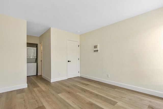 unfurnished room featuring light hardwood / wood-style floors and stacked washing maching and dryer