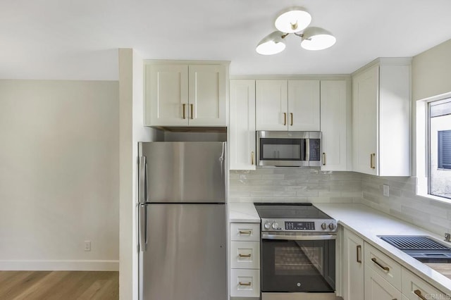 kitchen with appliances with stainless steel finishes, tasteful backsplash, light hardwood / wood-style flooring, and white cabinetry