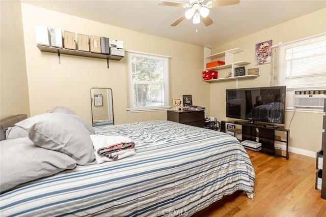 bedroom featuring hardwood / wood-style floors, ceiling fan, cooling unit, and multiple windows