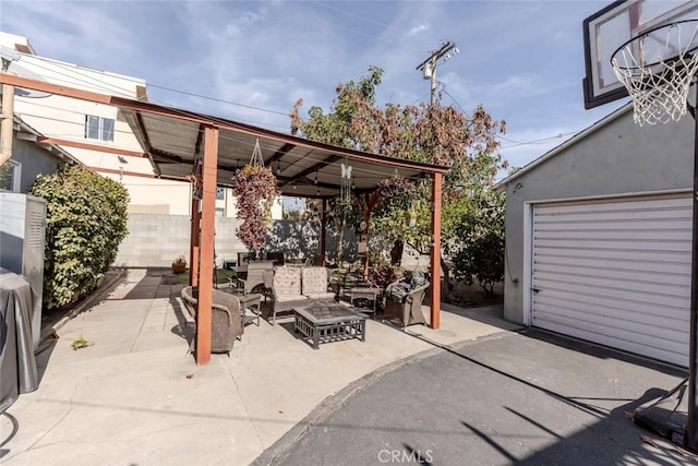 view of patio with a garage, an outdoor hangout area, and an outbuilding