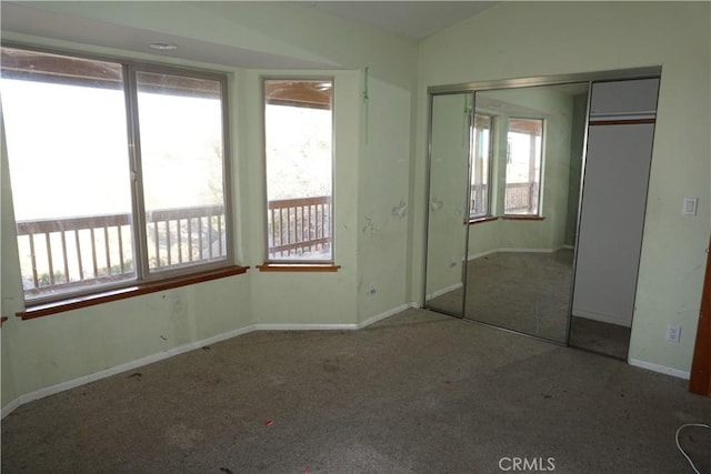 unfurnished bedroom featuring lofted ceiling, carpet floors, a closet, and baseboards