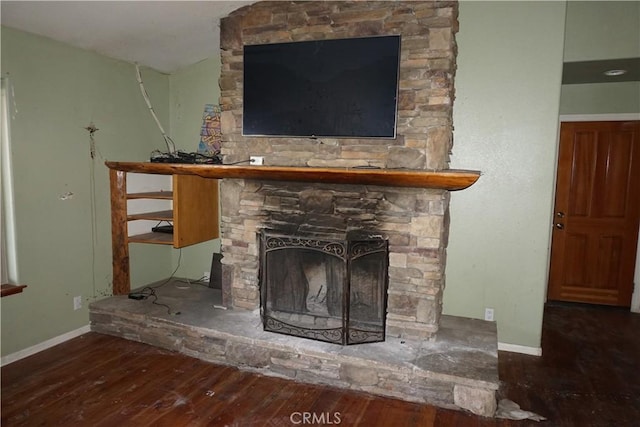 room details with baseboards, wood finished floors, and a stone fireplace