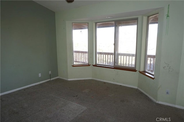 empty room with vaulted ceiling, carpet floors, and baseboards